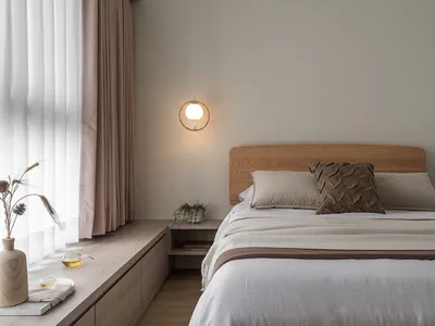 Minimalist bedroom featuring a wooden bed with beige bedding and curtains, a round pendant light, and a wooden window sill wi