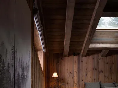 Minimalist bedroom with wooden furnishings, including a bed, table, and lamp.