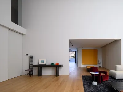 A modern Scandinavian living room with minimalist design elements, featuring a large wall, wooden flooring, and a mix of furn