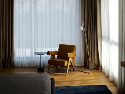 A minimalist bedroom with a wooden bed, fabric rug, and metal lamp.