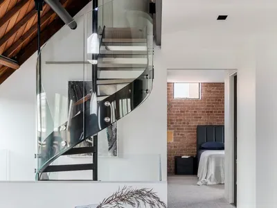 A modern bedroom featuring glass stairs and a wooden floor.