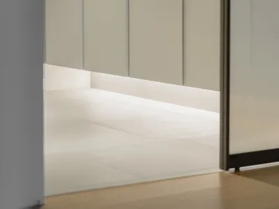A minimalist bedroom featuring white wall panels and a concrete floor, creating a serene and contemporary atmosphere.