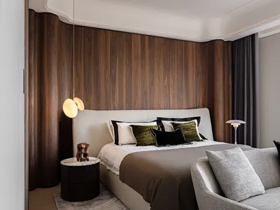 A modern bedroom with a white bed, brown wooden wall panels, and a white sofa.