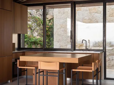 A modern kitchen featuring wooden cabinets and metal chairs.