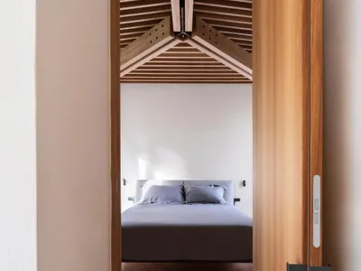 Modern minimalist bedroom featuring wooden beams and a simple design.
