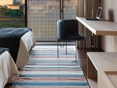 Modern minimalist bedroom featuring wooden furniture on striped rug