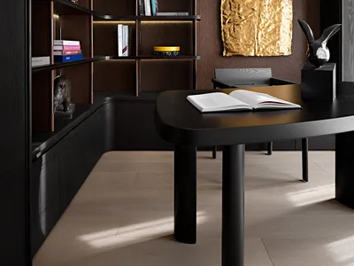 A modern black office with dark wood finishes and a gold abstract wall art piece.
