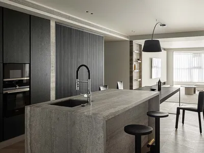 Modern minimalist kitchen with concrete countertops and metal faucet and stools.