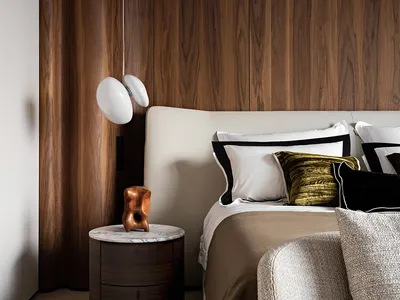 Minimalist bedroom with wood-paneled walls, marble bedside table, and fabric and leather upholstered furniture.