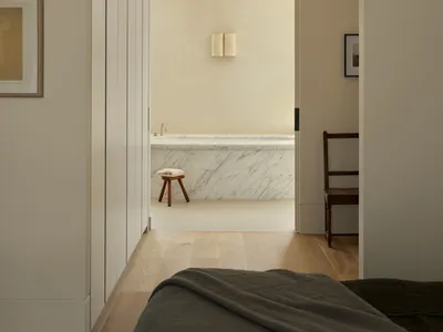 Modern minimalist bedroom with a marble bathtub in the background.