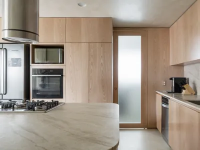 A modern kitchen featuring wooden cabinets, a marble countertop, and stainless steel appliances.