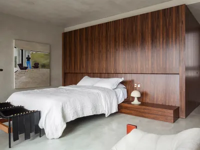 A minimalist bedroom featuring a bed with a wooden headboard and white bedding.