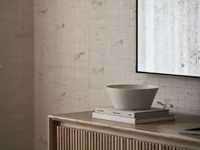A modern minimalist bedroom featuring a wooden sideboard with a matte surface.