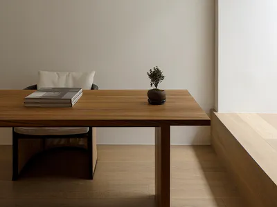 Minimalist home office with wooden desk and chair, minimalist decor, and white walls.