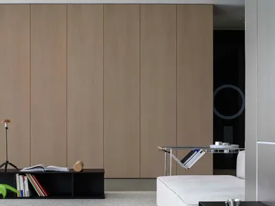 A minimalist living room with a white sofa, a black coffee table, and a large wooden cabinet in the background.