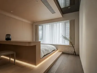 A minimalist bedroom featuring a wooden platform bed and a wooden desk with integrated lighting.