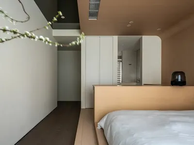 Minimalist bedroom with a wooden platform bed and upholstered bedding.