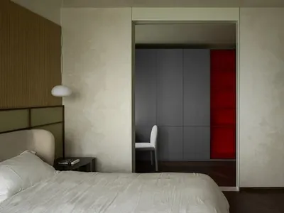 A minimalist bedroom with a white bed, white walls, and white fabric headboard, featuring a wooden floor.