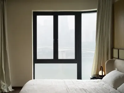 一間現代臥室，床上鋪著白色寢具，窗邊懸掛著白色窗簾。