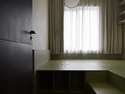 一間極簡現代臥室，採用綠色混凝土地板、木質家具與白色窗簾。