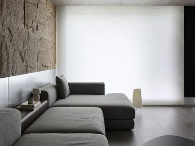 The image depicts an industrial-style living room with a modern concrete wall and a ceiling light fixture.