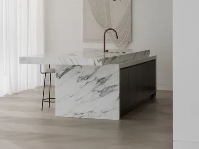 Modern kitchen with white marble countertops and black cabinetry.