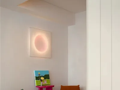 A cozy living room with plush cushions and a wooden floor, featuring a sunburst light fixture and colorful artwork.