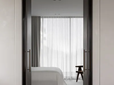 A minimalist bedroom with a bed dressed in white sheets, a patterned floor, and large windows dressed with white curtains.