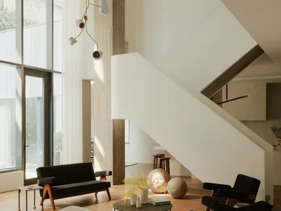 A minimalist living room featuring concrete columns, a white staircase, and a wooden floor.