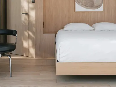 A minimalist bedroom featuring wooden interiors with a floating bed and hanging lamps.