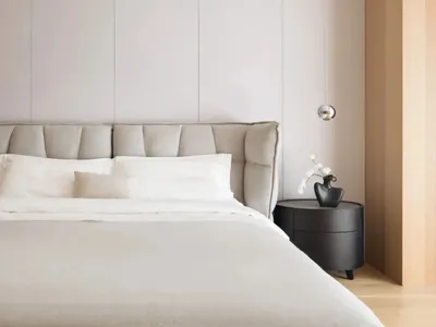 A minimalist bedroom featuring a bed with a fabric headboard against a wall with light gray panels.