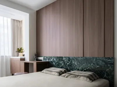 A modern minimalist bedroom with wood paneling and a marble headboard.