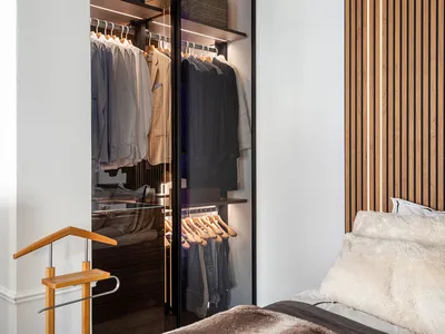 A modern bedroom with a brown wooden wall, built-in closet, and a bed covered in a fluffy blanket.
