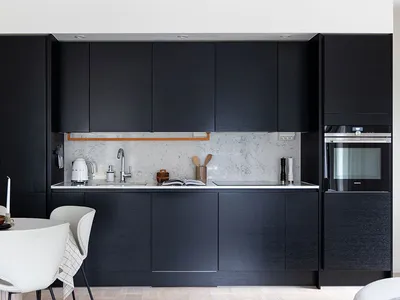 A modern kitchen featuring black wooden cabinets and a marble backsplash.