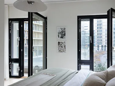 A minimalist bedroom featuring a bed with a glass top, a metal frame, and a concrete floor, adorned with polyester bedding an