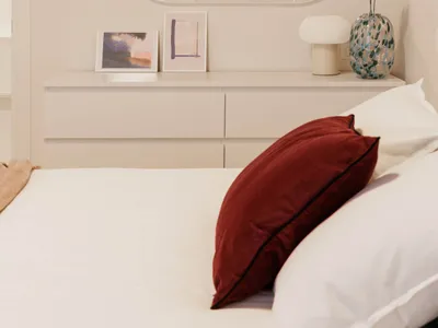 A minimalist bedroom with a white lamp and red pillows.