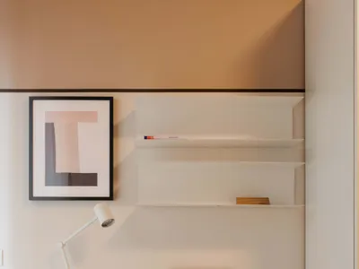 A modern home office setup with a white desk, minimalist shelves, and a beige chair.