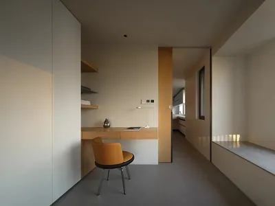A minimalist home office with a wooden desk and a yellow chair.