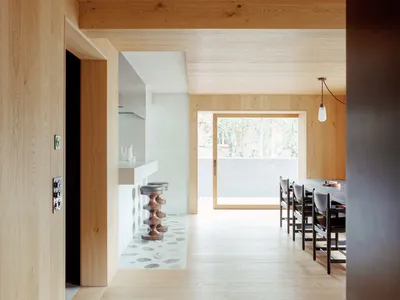 A minimalist open-plan kitchen dining room featuring wooden details and a spacious layout.
