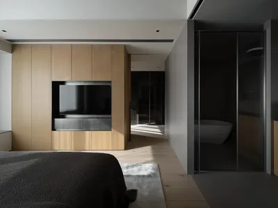 A modern minimalist bedroom featuring dark wood accents, glass panels, and concrete flooring.
