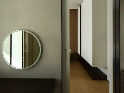 A minimalist living room with a concrete floor and a circular mirror on the wall.
