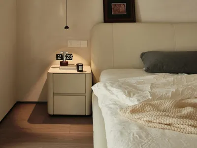 A minimalist bedroom with a bed, nightstand, and artwork on the wall.