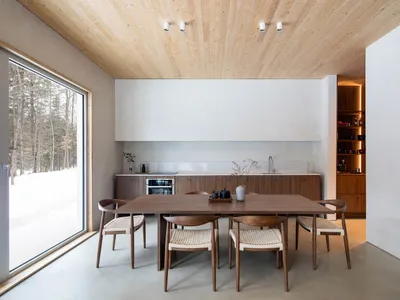 A modern kitchen with wooden cabinetry and a large window showing a snowy landscape.