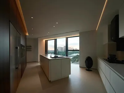 現代簡約廚房，配有白色櫥櫃、中島及不鏽鋼家電，設有大型窗戶可眺望城市景觀