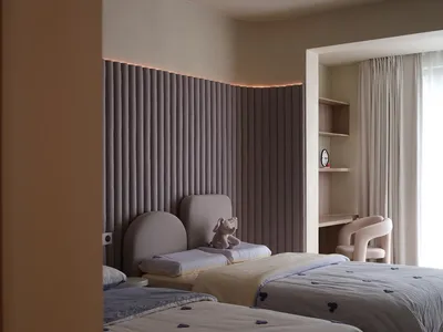 A modern minimalist bedroom with grey curtains, fabric headboards, and light wooden furnishings.