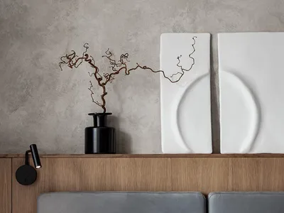 A minimalist bedroom featuring a concrete texture wall with a modern wooden headboard and simple bedding.