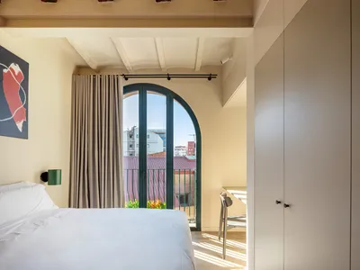 Modern minimalist bedroom with wooden beams on the ceiling, fabric curtains, and a white bed.