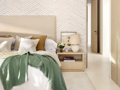 Modern minimalist bedroom featuring a bed with green and white textiles, a wooden nightstand, and a herringbone-patterned wal