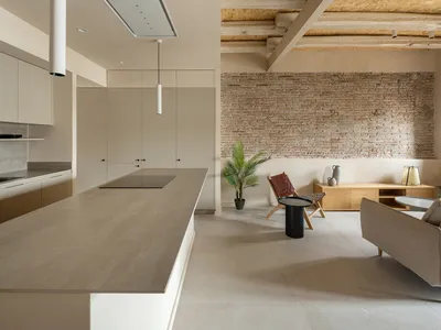 A modern kitchen with minimalist design features concrete countertops and walls.