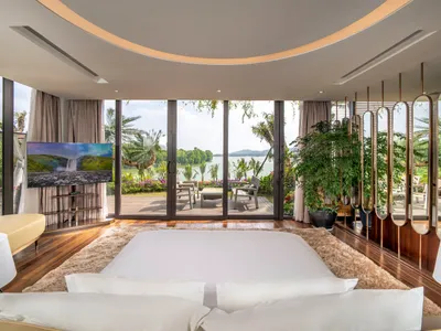A modern bedroom with a balcony overlooking a serene waterfront view.